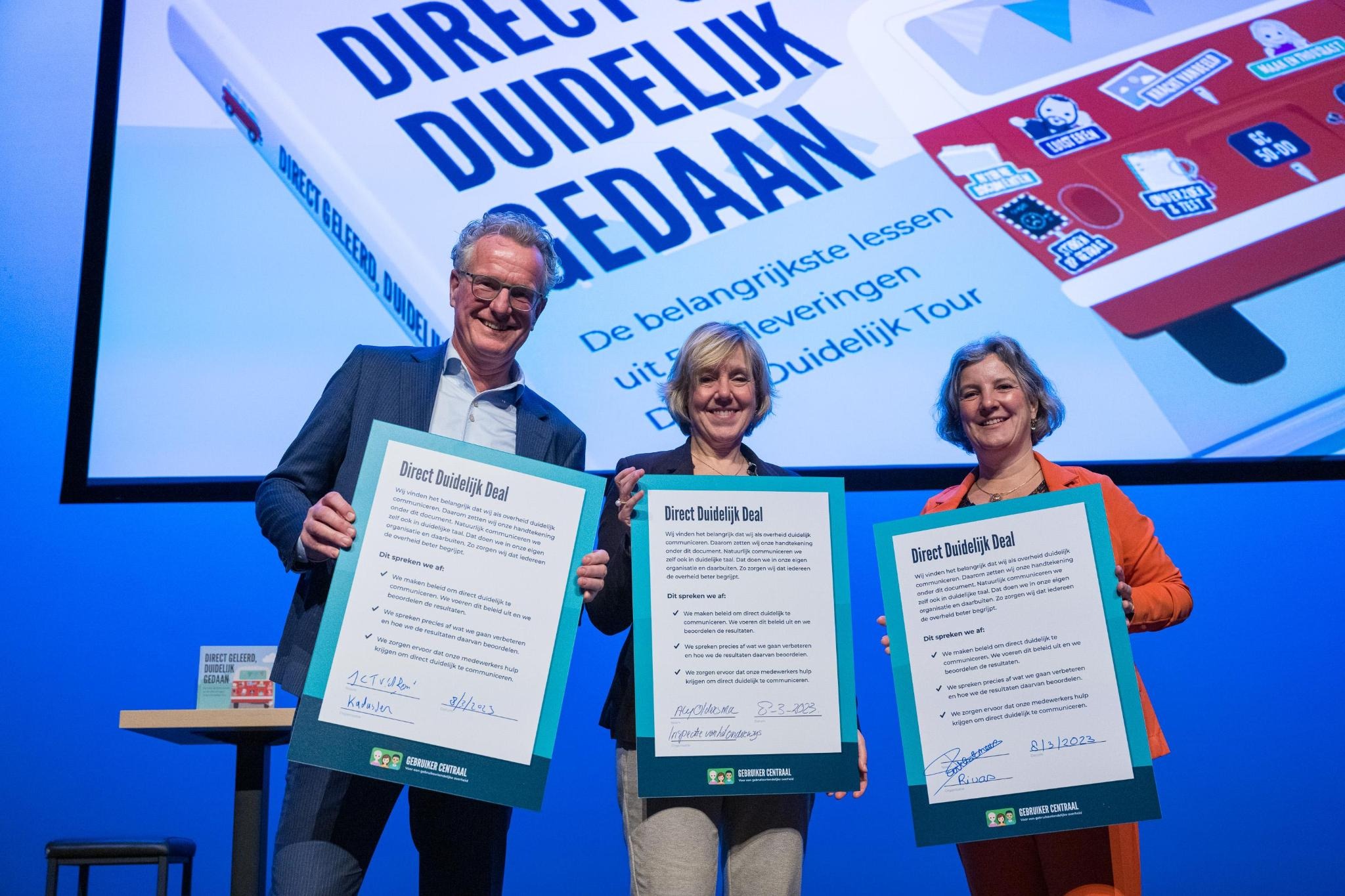 3 ondertekenaars laten de Direct Duidelijk Deal zien. Van links naar rechts: Hans van den Bemt (Kadaster), Aly Oldersma (Onderwijsinspectie) en Mariëlle Bartholomeus (Rivas Zorggroep)